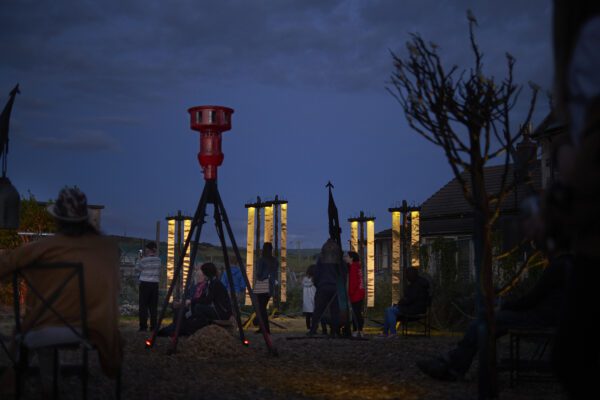 A night time image of a group of plinth structures with gold banners hanging from them.