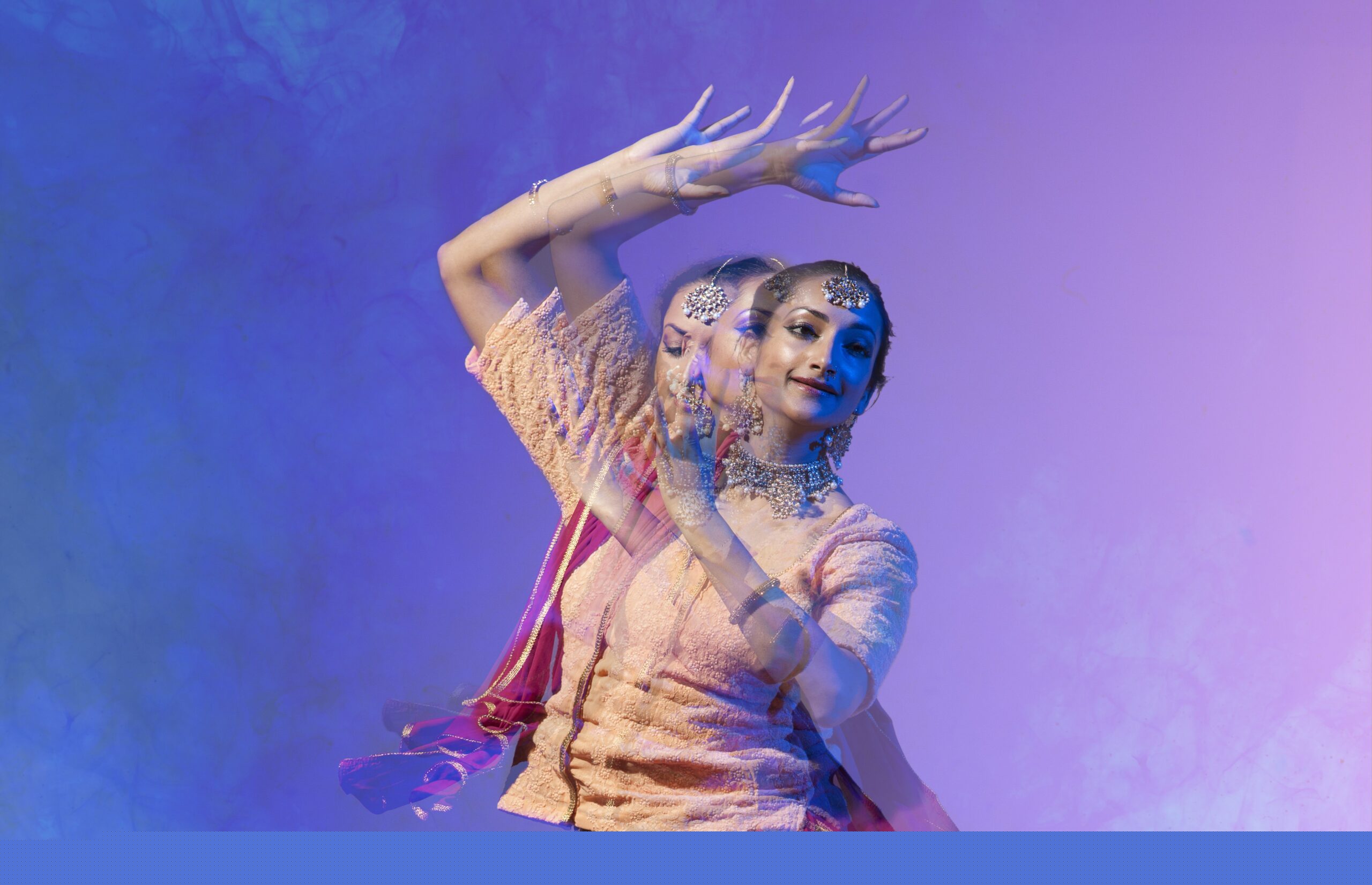 An image of an a South Asian female dancer dancing against a purple background.