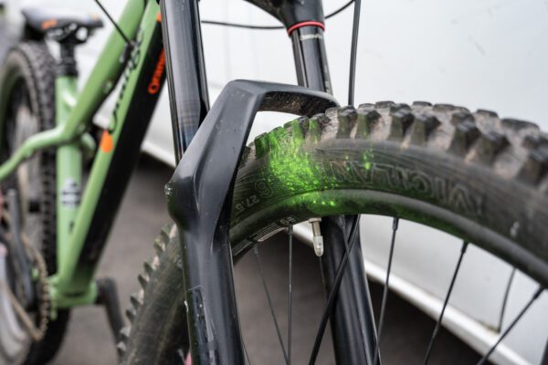 An close up image of a bicycle with some green spray paint on the wheel.