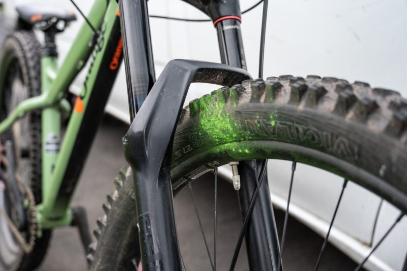 An close up image of a bicycle with some green spray paint on the wheel.
