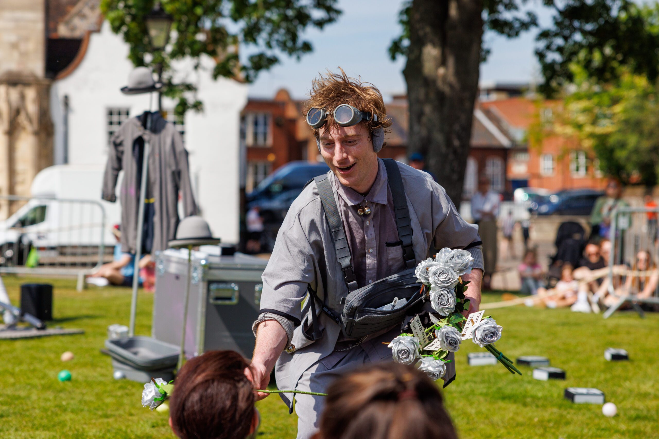 An image of a male performer wearing grey handing out grey roses to the audience