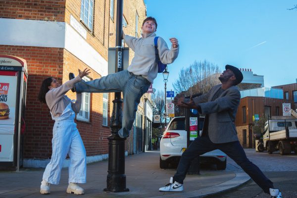 An image of three male dancers around a lamppost.