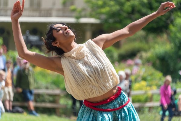 An image of a female dancer with her arms outstretched wearing traditional Indian dress