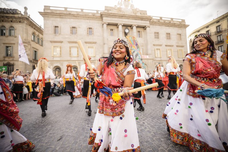 Extraordinary new outdoor art for everyone. We're a network of 35 festivals who commission and co-create outdoor art across the country. An image of street performers with 2 females wearing traditional female dress in the foreground.